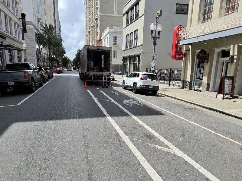 A box truck stopped in a painted bike lane on a downtown New Orleans street