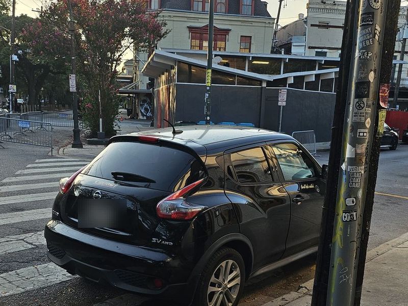 A car parked across a marked crosswalk at a New Orleans corner