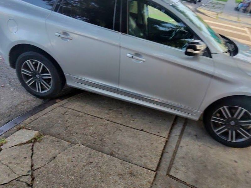 A silver SUV parked across a residential sidewalk in New Orleans